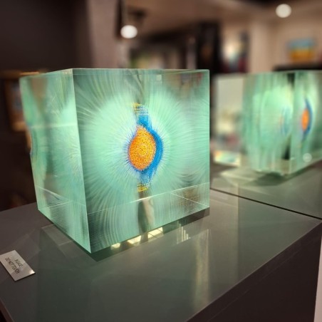 Un grand cube en verre transparent, renfermant un motif circulaire vert qui flotte à l’intérieur, de l'artiste Grootens