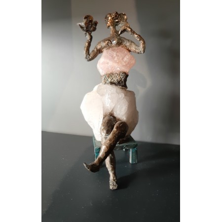 Escultura en bronce y cristal de roca de una mujer sentada con un pájaro de la artista Elisabeth Brainos